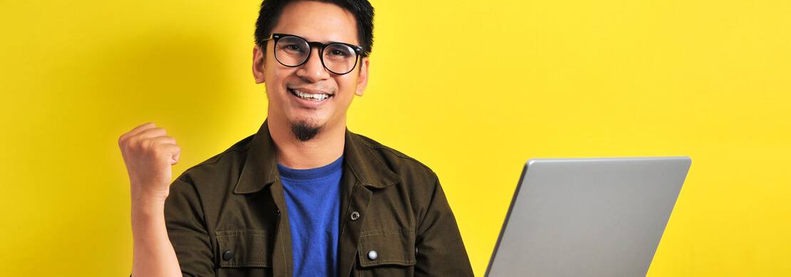 man holding a laptop happy from winning