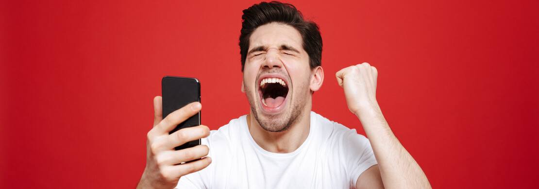 young man super excited about winning a progressive jackpot on his phone with a red background