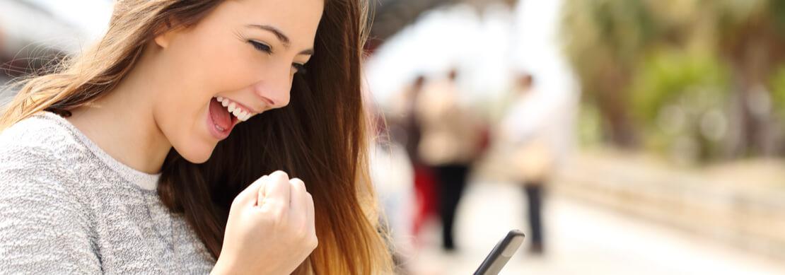 happy woman after a win playing Jackpot Capital slots on her phone