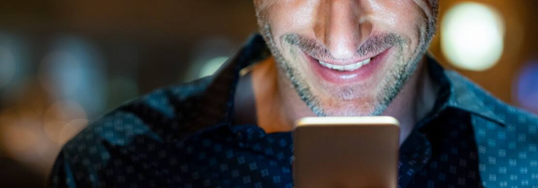 man playing at Jackpot Capital smiling at his phone