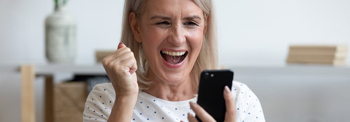 a middle aged woman playing Jackpot Capital on her phone and celebrating a win