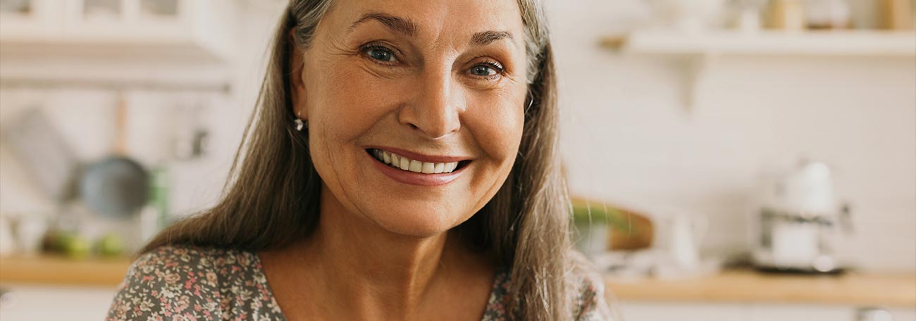 an attractive older woman with a broad smile in her kitchen