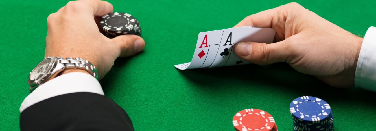 poker player with pocket aces contemplating his next bet. He is wearing a long sleeved white shirt and a suit