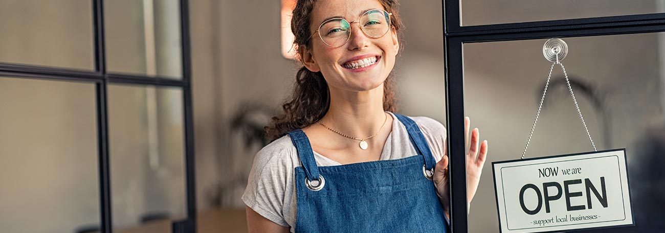 A woman in her twenties or thirties opening her business with a wide smile and a totally positive attitude.