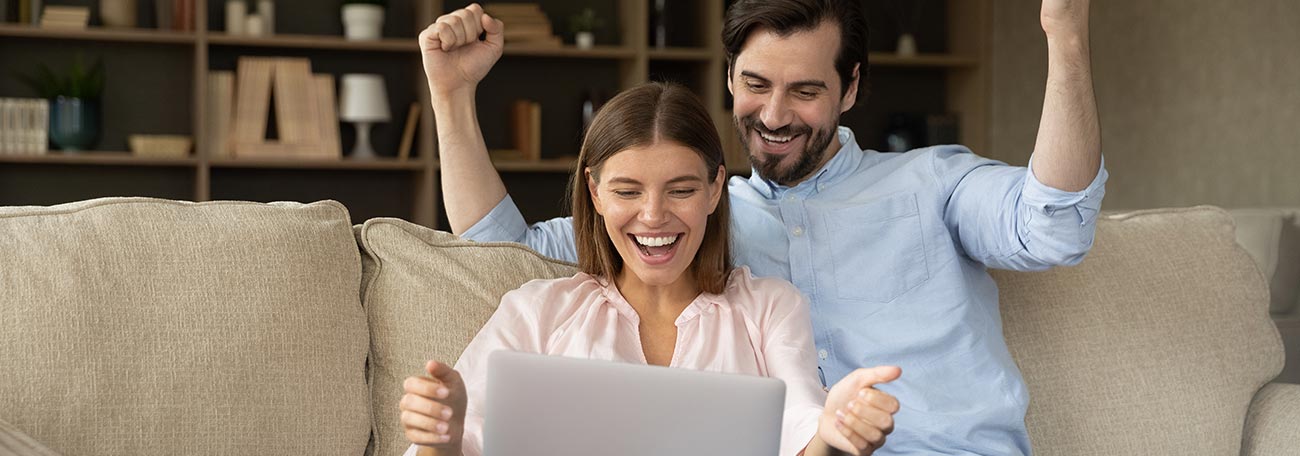 attractive young couple on the sofa happily rejoicing winning at an online acsino