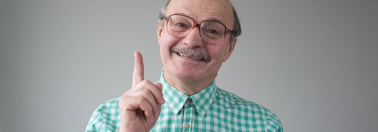 older man with small mustache giving advice with a genuine smile on his face