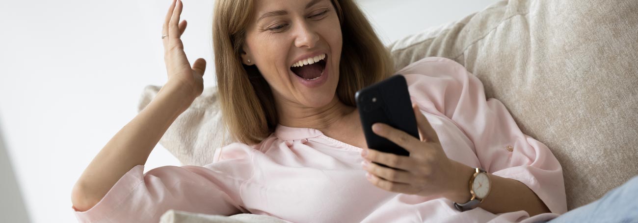 a young woman, sitting comfortably on the sofa, enjoying online casino games on her mobile device