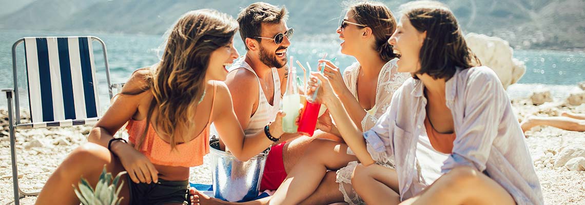 four friends, three women and a man, enjoying a  picnic by a mountain lake with the mountains in the background