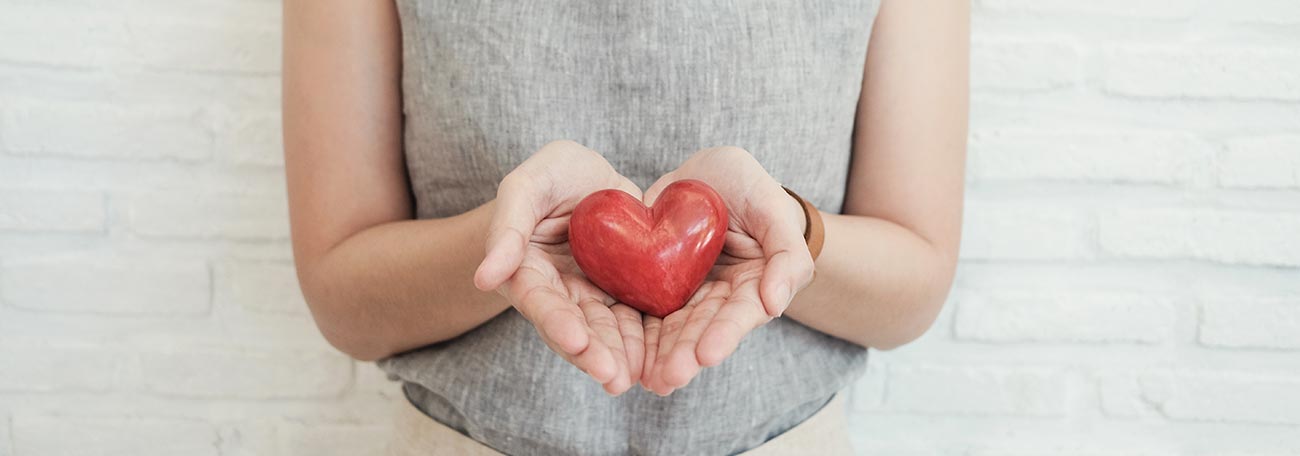 an attractive woman holding a red heart to symbolize responsible health and the love that leads people to be responsible 