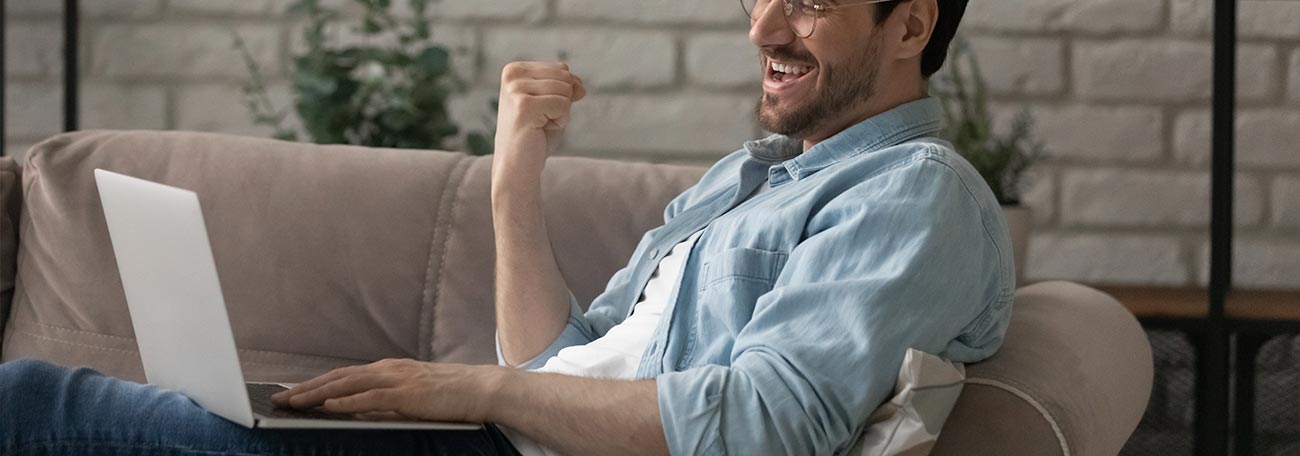 thirty-something man with short beard and moustache and unbuttoned business shirt relaxing on sofa playing online casino games