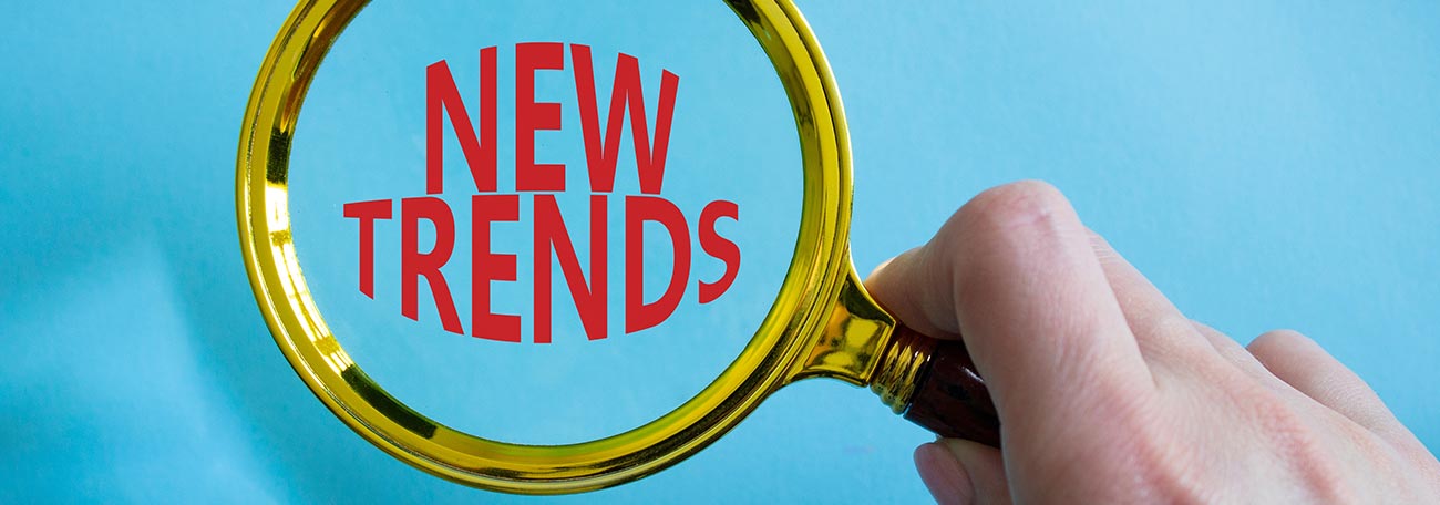 a woman's hand holding a magnifying glass over the words "new trends" to demonstare studying ternds 