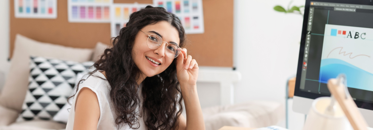 young, female graphic artist working in comfortable office possibly her living room with sofa in background