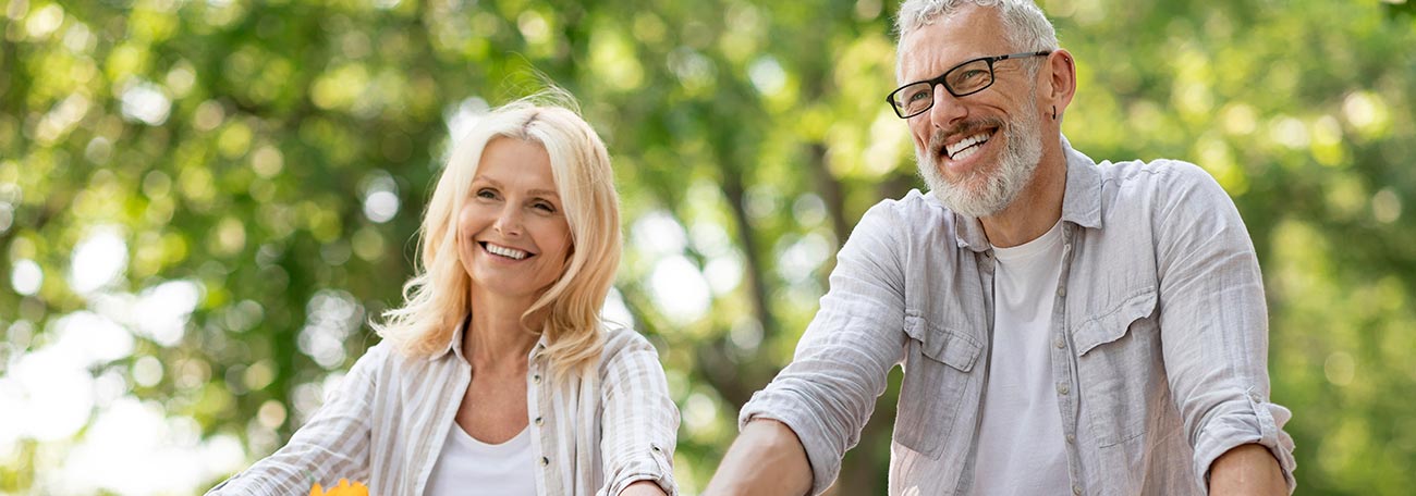 happy older couple on a bike trip. The woman has a basket with sunflowers