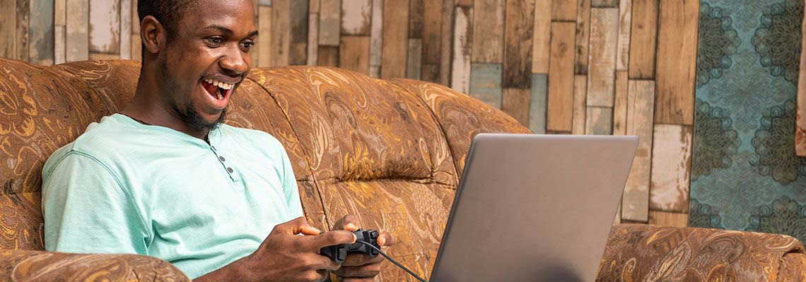 twenty something man playing online casino games while sitting comfortably on a large soft armchair